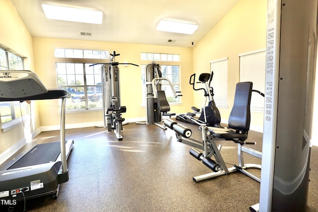 gym with visible vents, vaulted ceiling, and baseboards