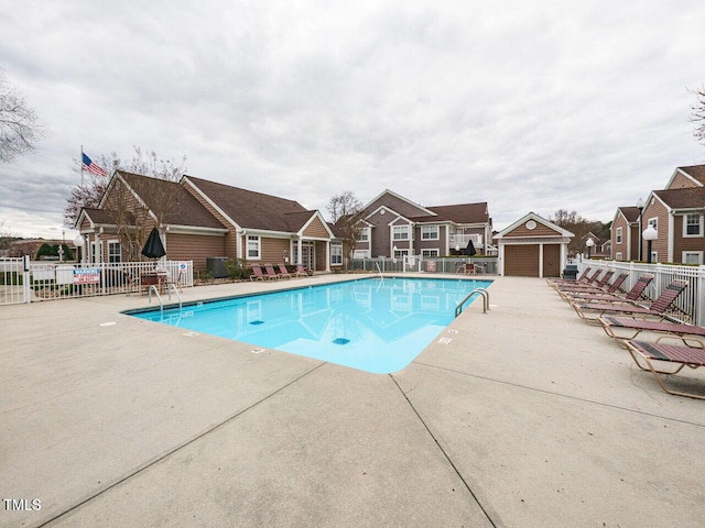 pool featuring a residential view, fence, and an outdoor structure