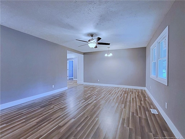 spare room with a textured ceiling, wood-type flooring, and ceiling fan with notable chandelier