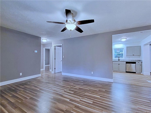 unfurnished living room featuring sink, ceiling fan, a textured ceiling, and light hardwood / wood-style flooring