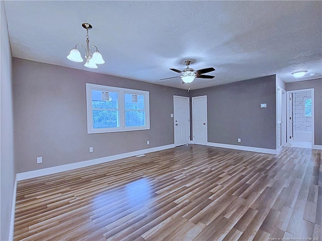 empty room featuring light hardwood / wood-style floors, a textured ceiling, and ceiling fan with notable chandelier