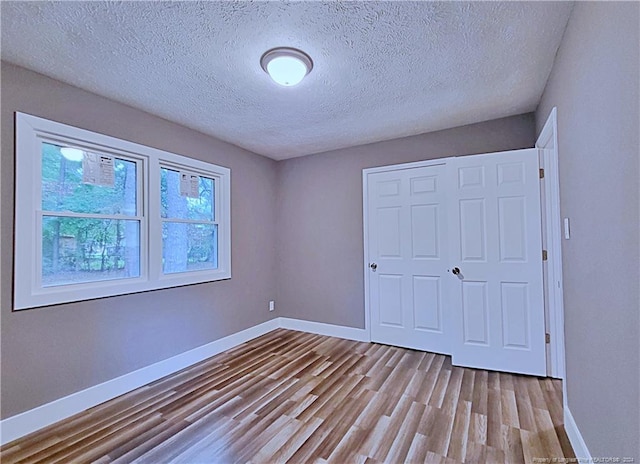 unfurnished bedroom featuring light hardwood / wood-style flooring, a textured ceiling, and a closet