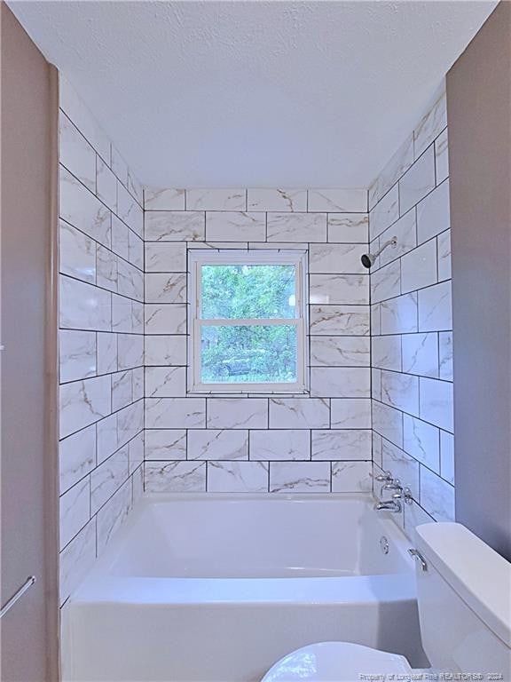 bathroom featuring toilet and tiled shower / bath