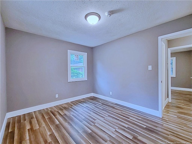 spare room with a textured ceiling and light hardwood / wood-style flooring