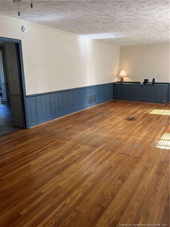 spare room with ornamental molding, a textured ceiling, and dark hardwood / wood-style flooring