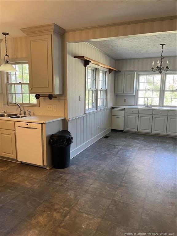 kitchen with sink, white dishwasher, a wealth of natural light, and hanging light fixtures