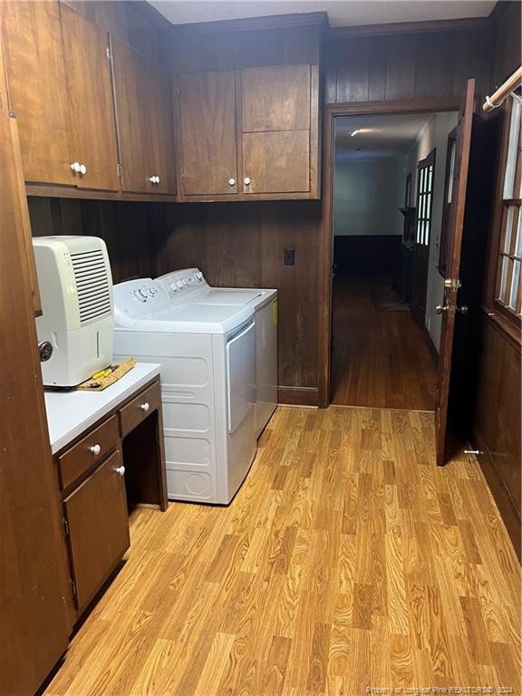 laundry area with ornamental molding, light hardwood / wood-style flooring, washer and dryer, and cabinets