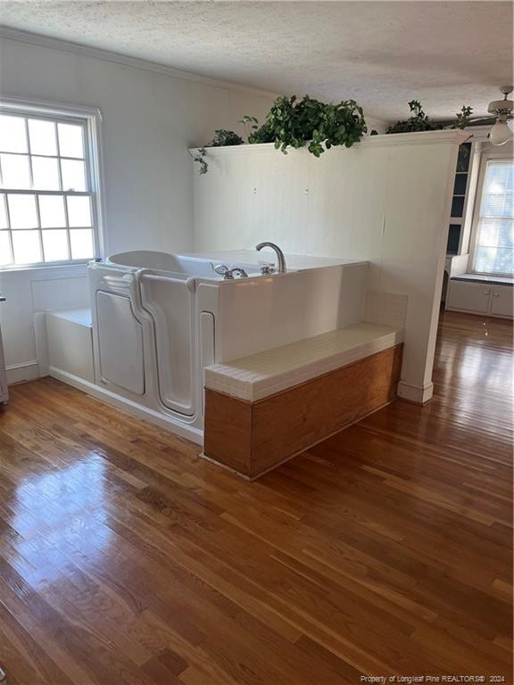 washroom with a textured ceiling, dark wood-type flooring, and ceiling fan