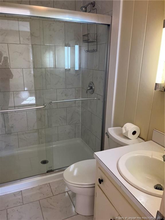 bathroom featuring vanity, a shower with shower door, and toilet