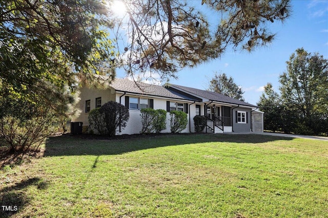 ranch-style home featuring cooling unit and a front lawn