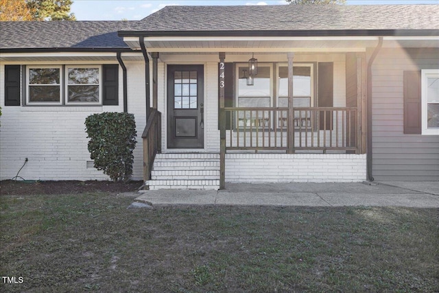 view of exterior entry with a porch and a lawn