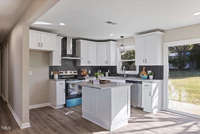 kitchen featuring white cabinetry, hardwood / wood-style flooring, wall chimney range hood, and appliances with stainless steel finishes