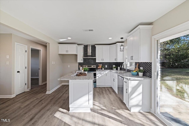 kitchen featuring appliances with stainless steel finishes, light wood-type flooring, a center island, white cabinetry, and pendant lighting