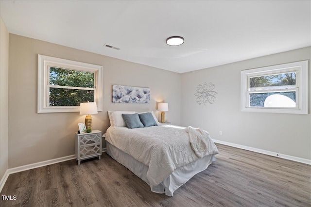 bedroom with multiple windows and dark wood-type flooring