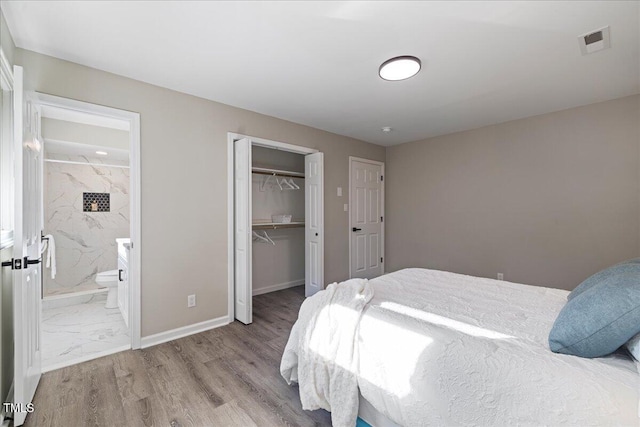 bedroom with a closet, ensuite bathroom, and light hardwood / wood-style floors