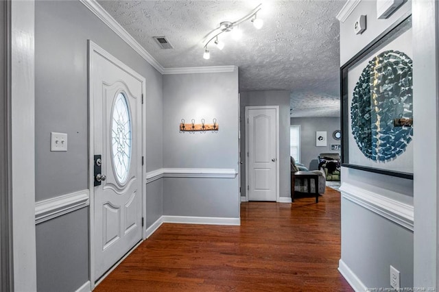 foyer with ornamental molding, dark wood-type flooring, and a textured ceiling