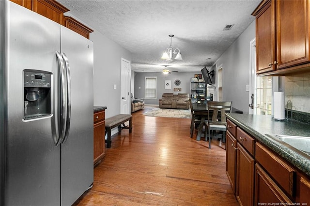 kitchen with a textured ceiling, hardwood / wood-style flooring, a healthy amount of sunlight, and stainless steel fridge with ice dispenser