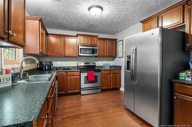 kitchen featuring hardwood / wood-style floors, sink, stainless steel appliances, and a textured ceiling