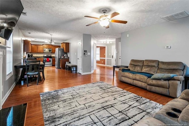 living room featuring ceiling fan, hardwood / wood-style flooring, and a textured ceiling