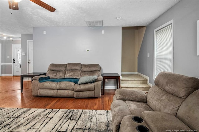 living room with a textured ceiling, hardwood / wood-style flooring, and ceiling fan