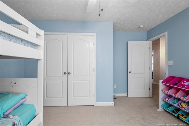 carpeted bedroom featuring a textured ceiling, a closet, and ceiling fan