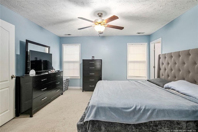 carpeted bedroom featuring ceiling fan and a textured ceiling