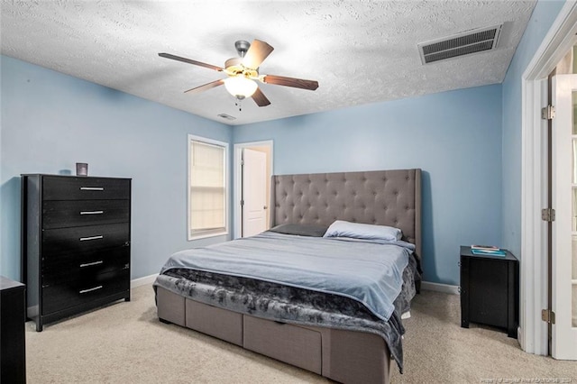 bedroom featuring a textured ceiling, light colored carpet, and ceiling fan