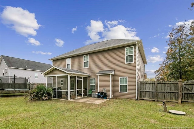 rear view of property featuring a sunroom, a lawn, a patio area, and a trampoline