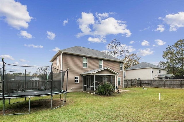 rear view of house featuring a yard, a trampoline, and a sunroom