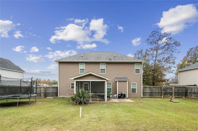 back of house featuring a patio, a sunroom, a trampoline, and a lawn