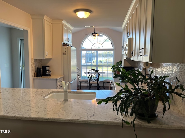 kitchen featuring sink, white appliances, white cabinetry, light stone counters, and tasteful backsplash