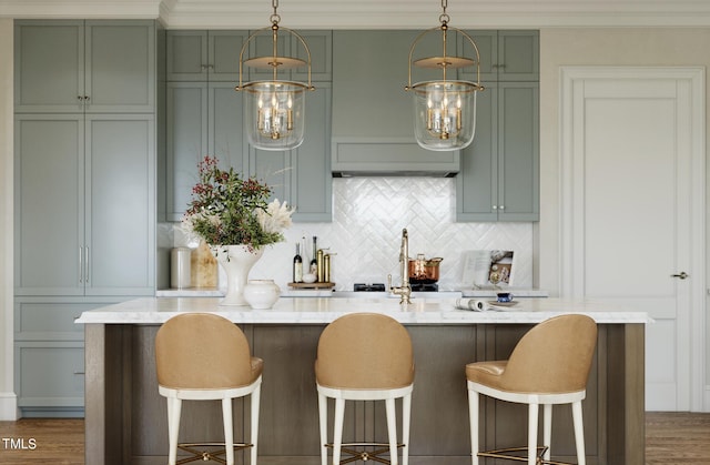 2606 Marchmont St # 101, Raleigh, NC 27608 - kitchen with green cabinets, tasteful backsplash, a kitchen island with sink, custom exhaust hood, and crown molding