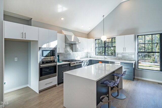 1414 Whippoorwill Ln, Chapel Hill, NC 27517 - kitchen with appliances with stainless steel finishes, wall chimney exhaust hood, light countertops, light wood finished floors, and white cabinetry
