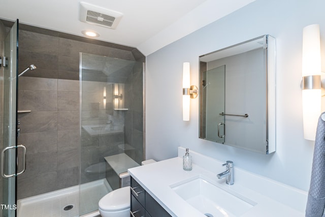 bathroom featuring toilet, vanity, and a shower with door