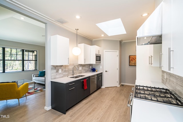 1414 Whippoorwill Ln, Chapel Hill, NC 27517 - kitchen featuring appliances with stainless steel finishes, a sink, a skylight, light countertops, and white cabinetry