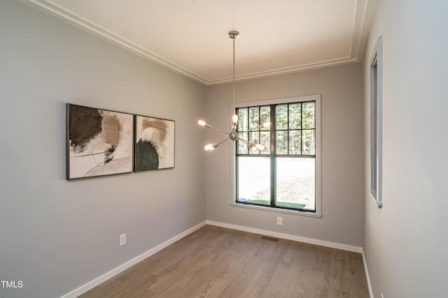 spare room featuring wood-type flooring, an inviting chandelier, and ornamental molding