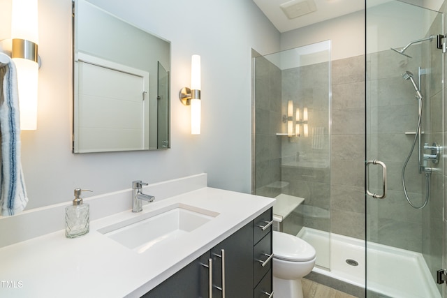 bathroom featuring a shower with shower door, vanity, and toilet