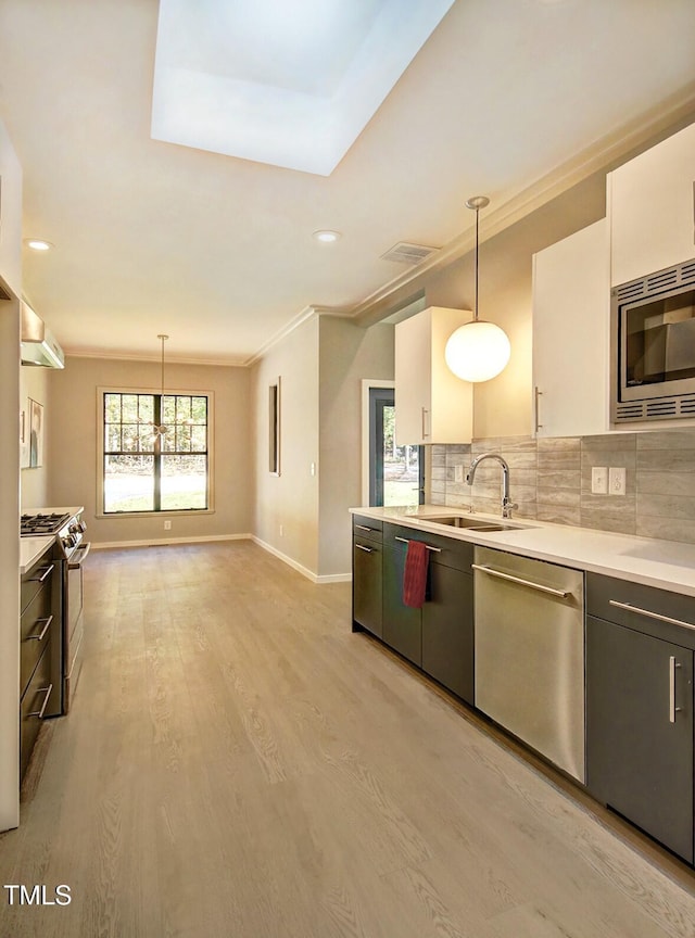 1414 Whippoorwill Ln, Chapel Hill, NC 27517 - kitchen featuring appliances with stainless steel finishes, light wood finished floors, light countertops, pendant lighting, and a sink