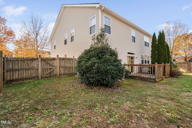 back of house featuring a lawn and a wooden deck