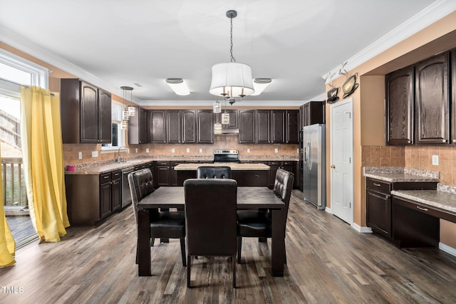 kitchen featuring dark brown cabinetry, hanging light fixtures, and appliances with stainless steel finishes