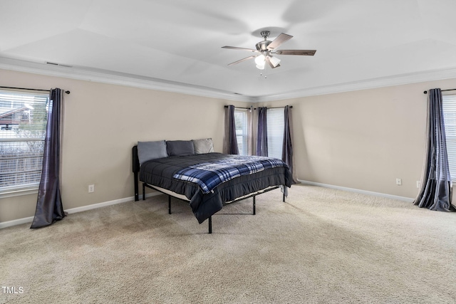 bedroom with ceiling fan, a raised ceiling, ornamental molding, and light carpet