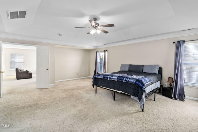 bedroom featuring light carpet, a raised ceiling, multiple windows, and ceiling fan