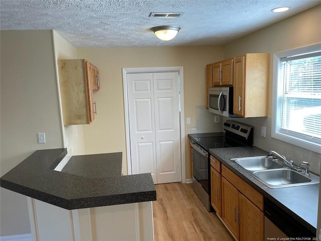 kitchen with backsplash, appliances with stainless steel finishes, a textured ceiling, light hardwood / wood-style flooring, and sink