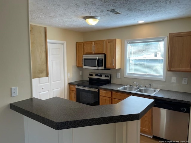 kitchen featuring appliances with stainless steel finishes, kitchen peninsula, tasteful backsplash, and sink