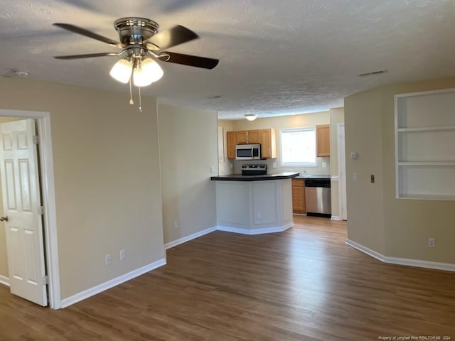 kitchen featuring hardwood / wood-style floors, ceiling fan, stainless steel appliances, and a textured ceiling