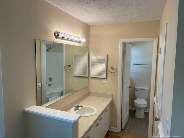 bathroom featuring toilet, a textured ceiling, hardwood / wood-style flooring, and vanity