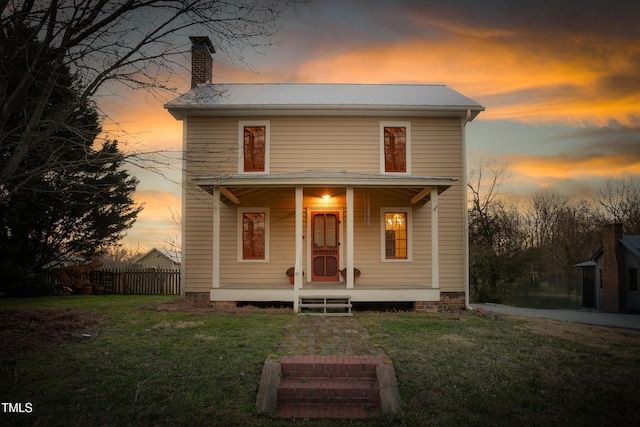 view of front of house with a porch, a yard, fence, and a chimney