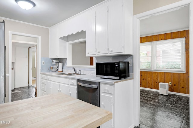 kitchen with stainless steel appliances, white cabinetry, sink, crown molding, and wooden walls