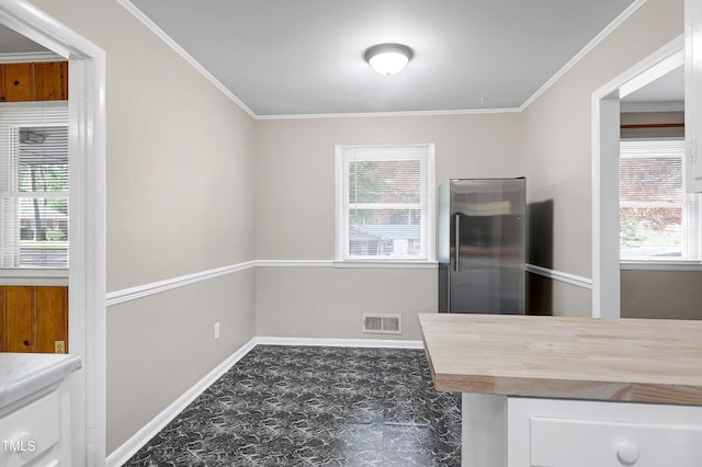 unfurnished dining area with a wealth of natural light and crown molding