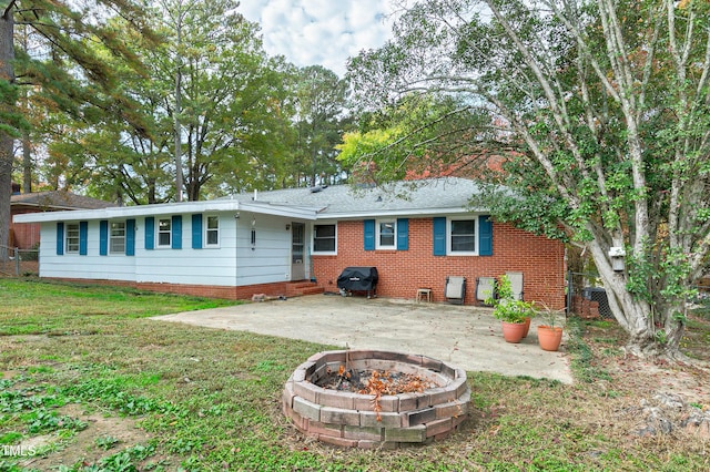 back of house featuring a patio, a yard, and a fire pit